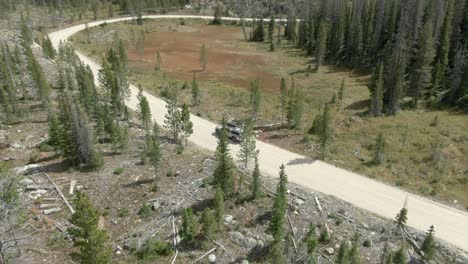 Aerial-following-truck-on-dirt-road-towards-curve-in-Colorado