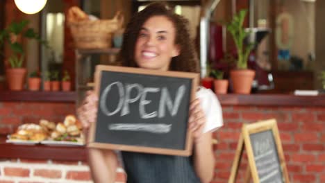 Smiling-barista-holding-an-open-signboard
