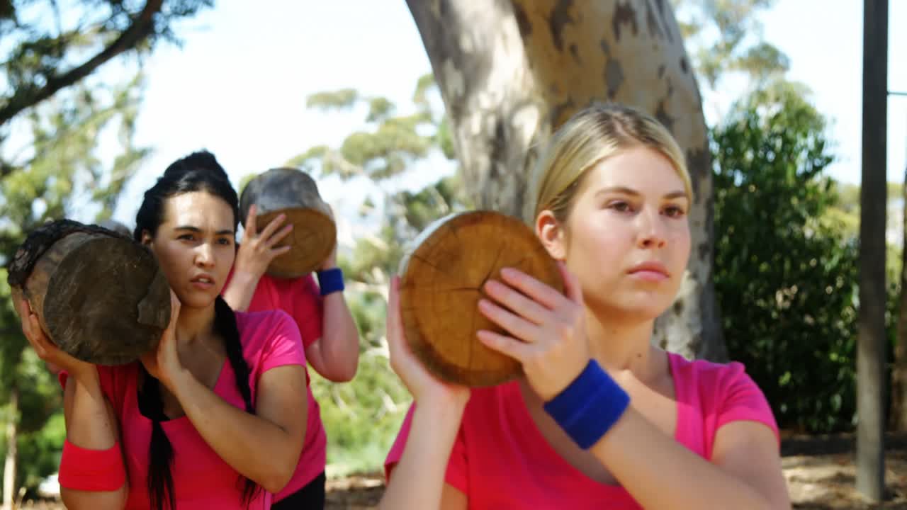 grupo de mujeres que llevan un tronco pesado durante una carrera de obstáculos