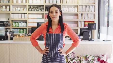 Video-of-happy-biracial-waitress-in-apron-standing-in-coffee-shop