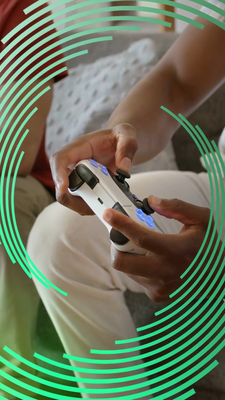 Vertical video: Man using pad pressing, causing green ring over hands, friend watching while gaming