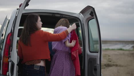 two women packing clothes in a van for a road trip