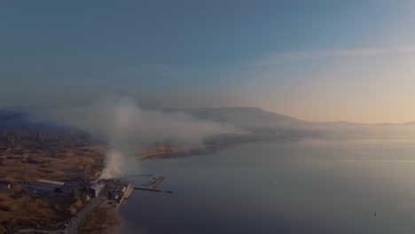 Luftaufnahme-über-Der-Fabrik-An-Der-Küste-Von-Lesbos-Neben-Der-Ägäis,-Die-Rauch-Aus-Dem-Schornstein-Abpumpt