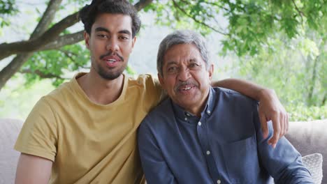 portrait of happy biracial father and son sitting together at patio