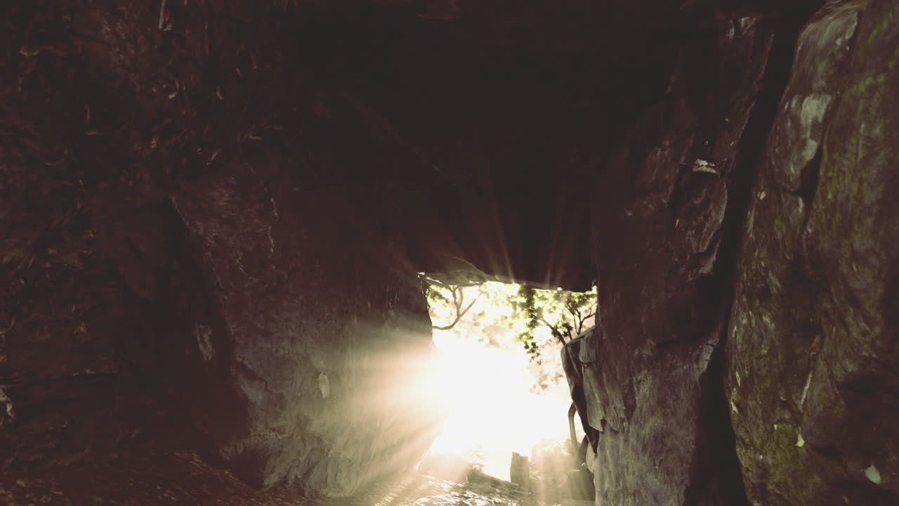 La luce irrompe attraverso l'apertura di una grotta, illuminando l'ambiente roccioso circostante