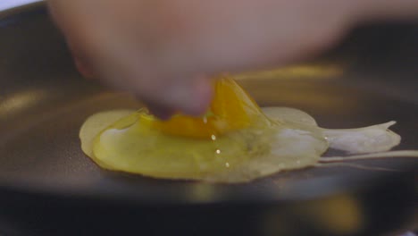 Egg Popping Out of Shell as Chef Lowers Egg Gently onto Pan with Yolk in Center. Heat from Below Starts to Cook Breakfast Protein Meal