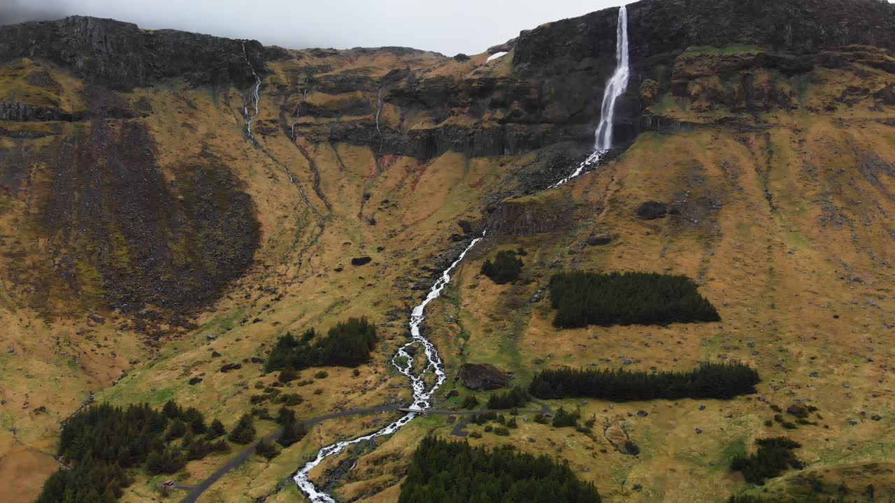 video aéreo que va hacia la asombrosa cascada bjarnarfoss ubicada en las altas montañas de islandia