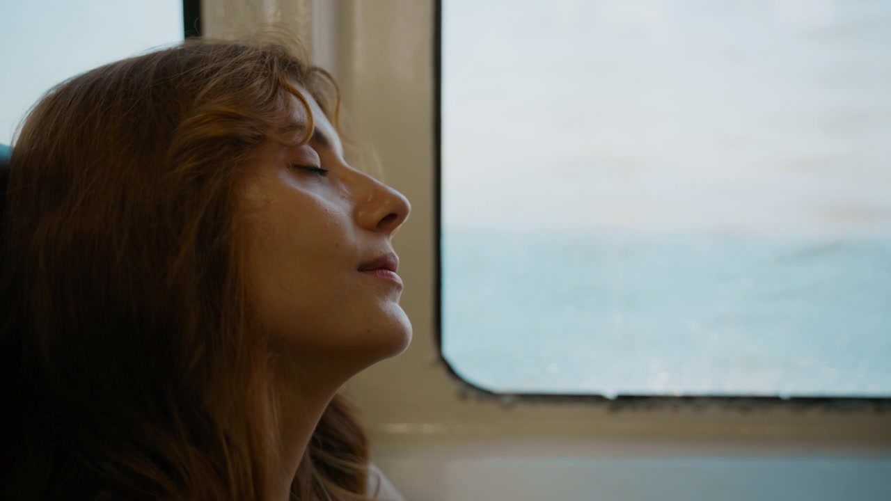 Una donna dorme seduta su un traghetto veloce per Capri.