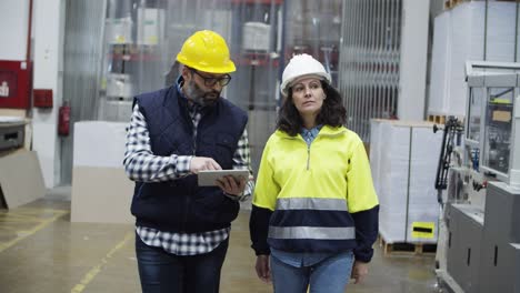 Front-view-of-machine-operators-with-tablet-walking-at-factory