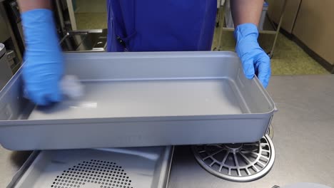 a member of an operating department cleans instrument containers with a cleaning tissue