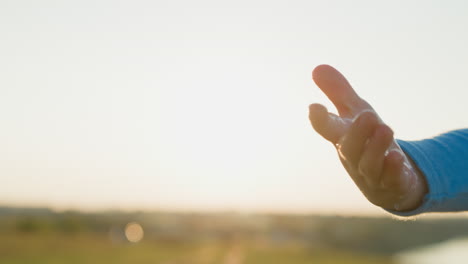 la mano extendida hacia la puesta de sol