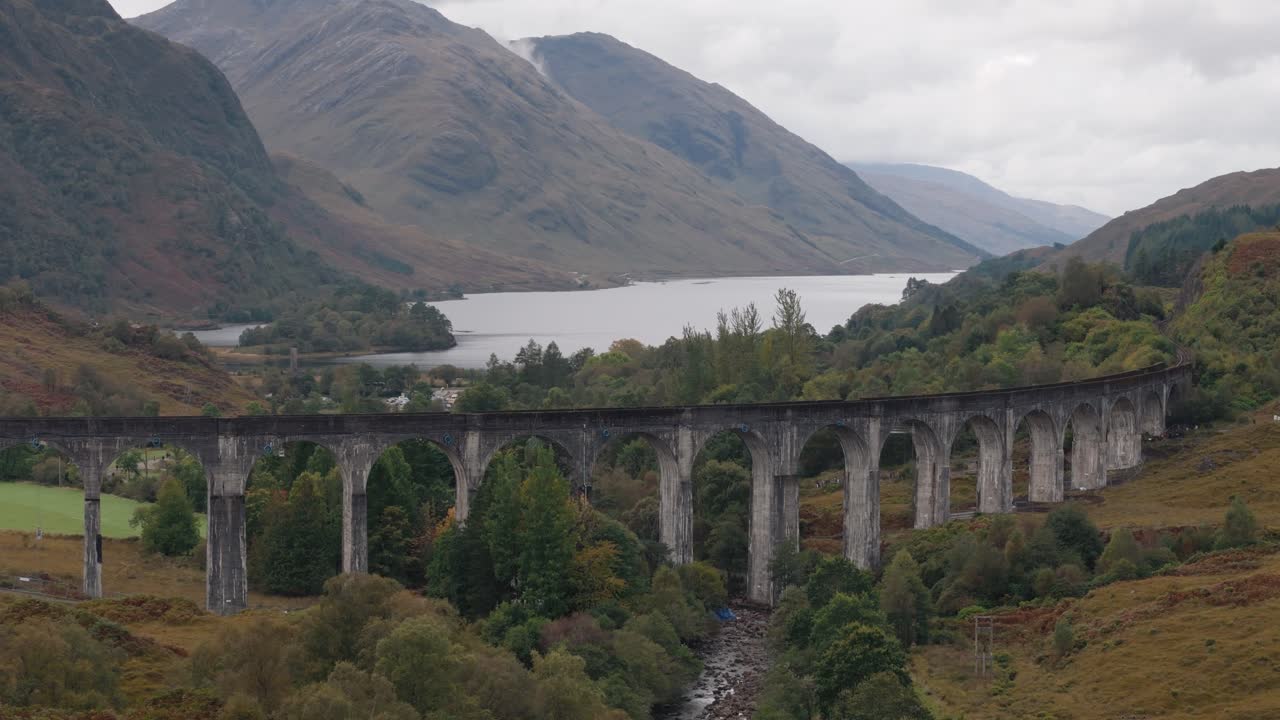 Circling right over Glenfinnan Viaduct, capturing lake and Highland mountains in lush landscape