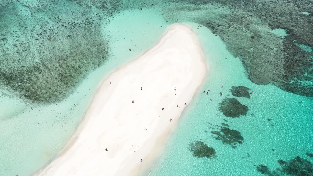 top-down aerial drone view of a secluded sandbar in Fiji. Crystal-clear turquoise waters and vibrant coral reefs surround this tiny, untouched tropical paradise