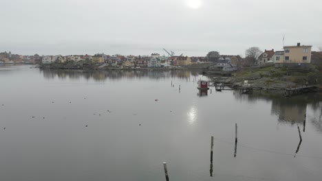 A-scenic-view-of-small-wooden-bridges-on-still-water,-a-group-of-birds,-a-saunaraft-and-the-beautiful-cityscape-of-Karlskrona,-Sweden-in-the-background