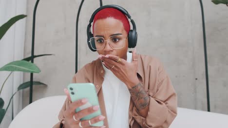 young shocked african american woman covers mouth after reading news on phone