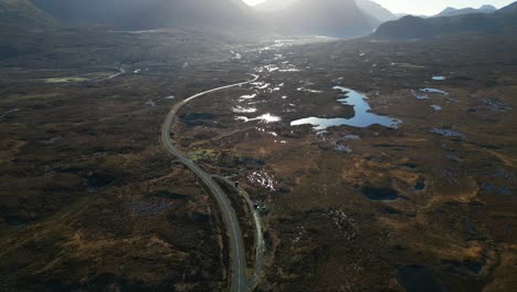 pan across scottish highland road and wilderness with dawn sunlight reflecting off water at sligachan isle of skye