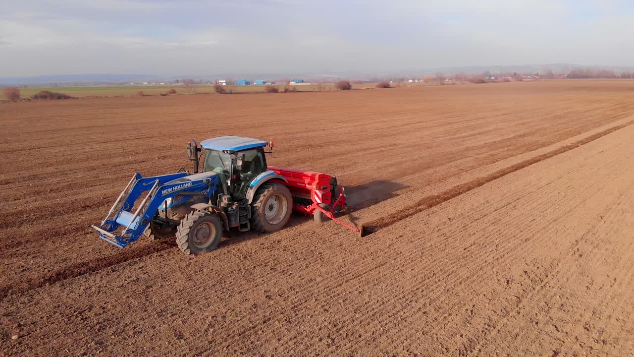 Tractor working in agricultural field, cultivating and ploughing dry soil, aerial view.