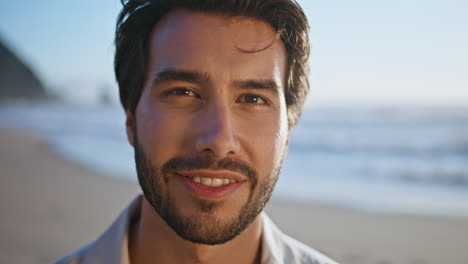 closeup hispanic man smiling standing on sunny beach. portrait happy bearded guy