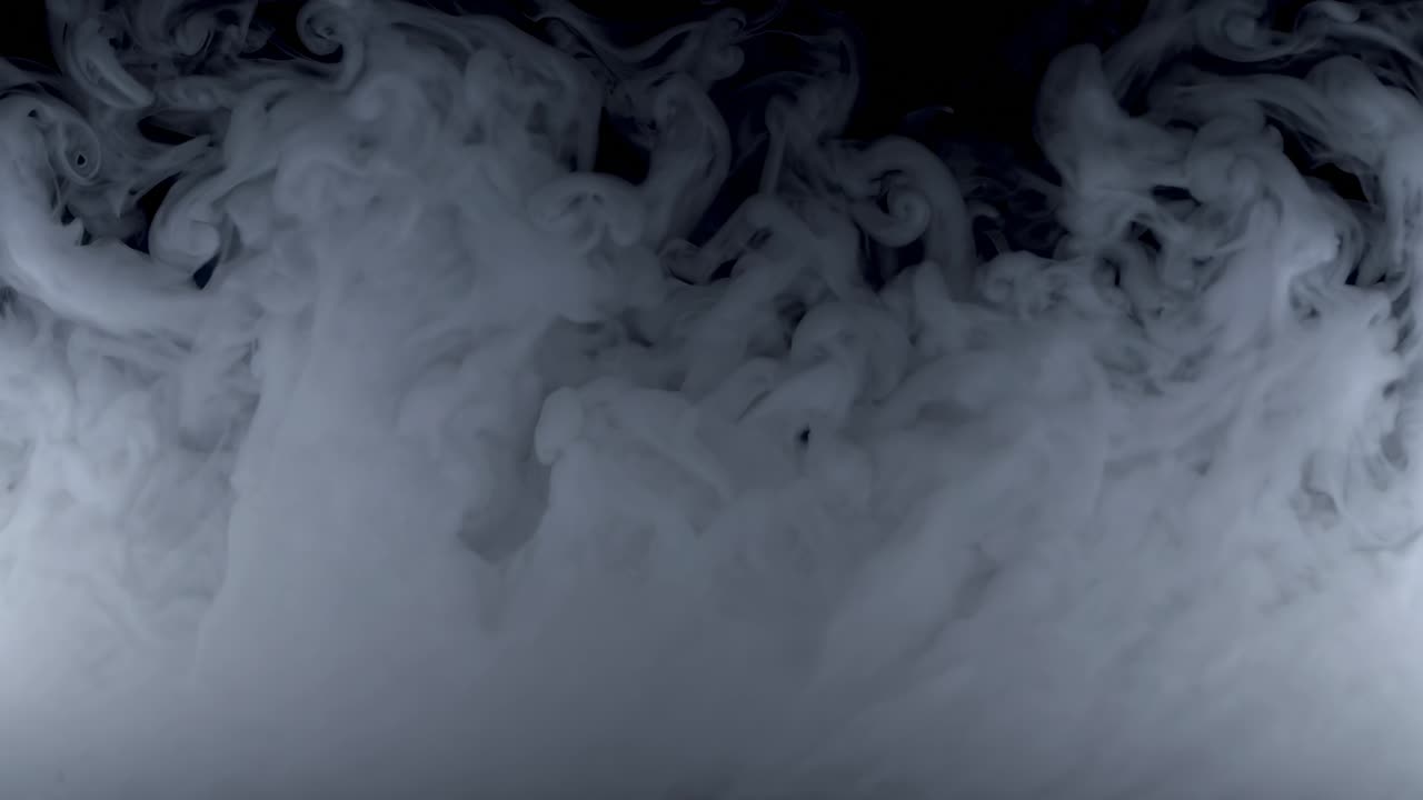 A captivating video of swirling white smoke against a black background, captured from a low angle