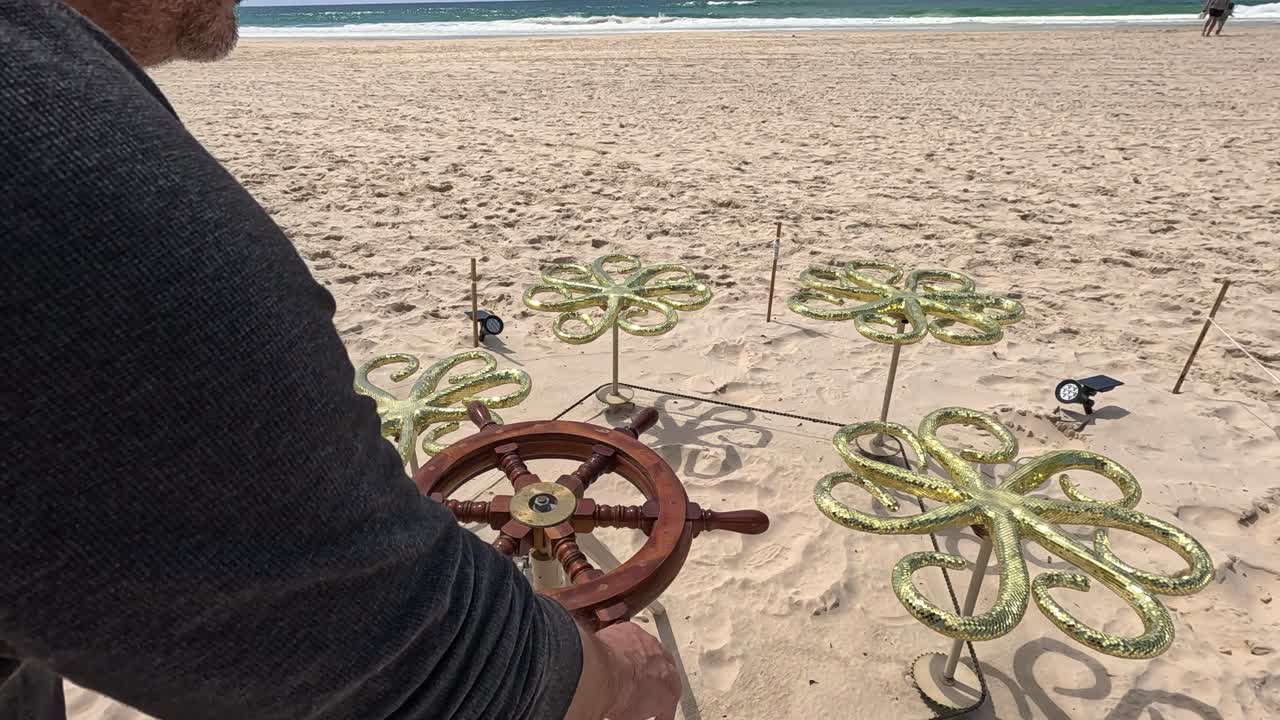 hombre opera una escultura en una playa de arena