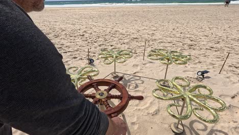 hombre opera una escultura en una playa de arena