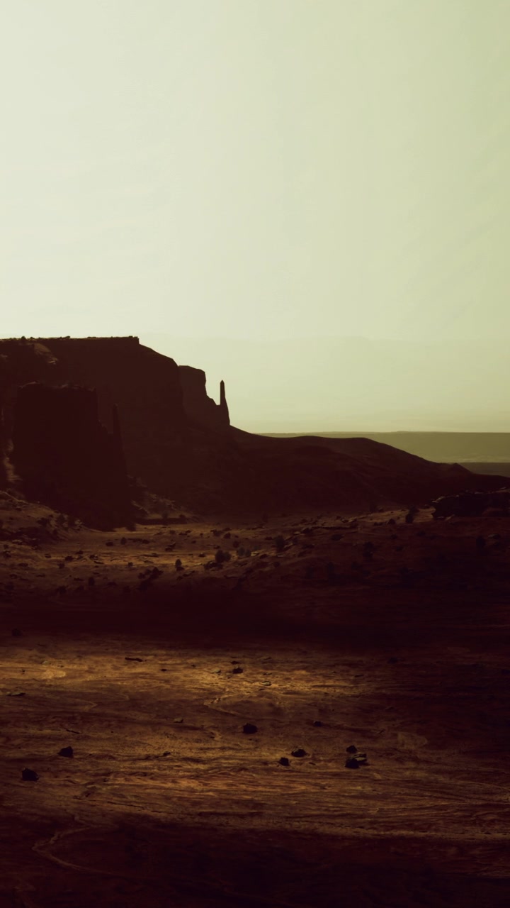 Sunset over rocky landscape with distant cliffs and open terrain in desert