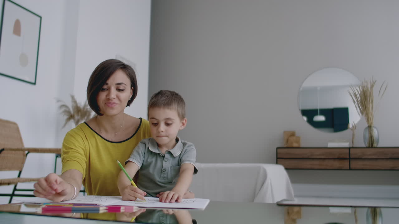 mujer joven y niño dibujando juntos haciendo un cuadro con lápices en plano