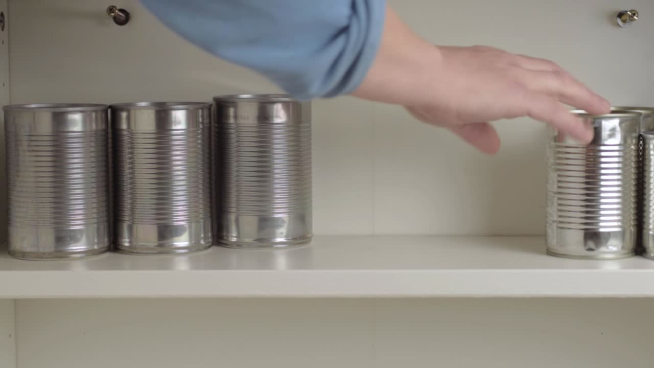 sacando latas de aluminio del estante del armario de alimentos
