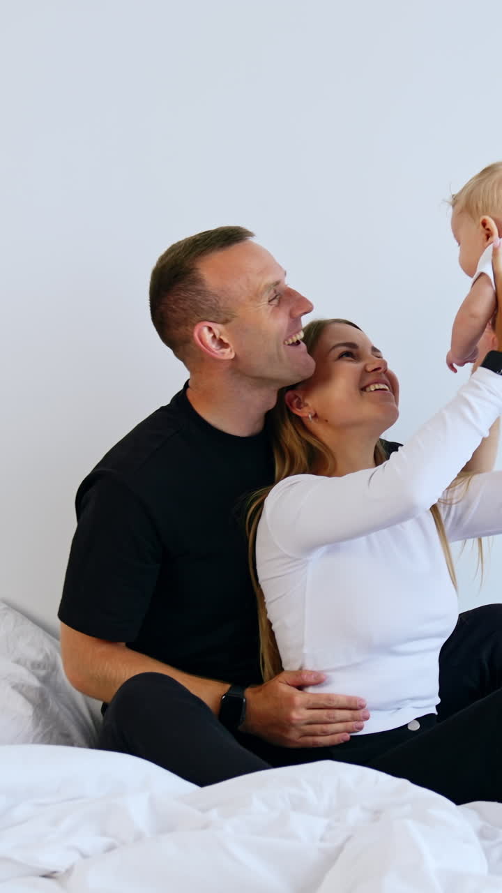 Donna tiene in braccio il suo grazioso bambino. Genitori felici sorridono al loro adorabile neonato. Video verticale
