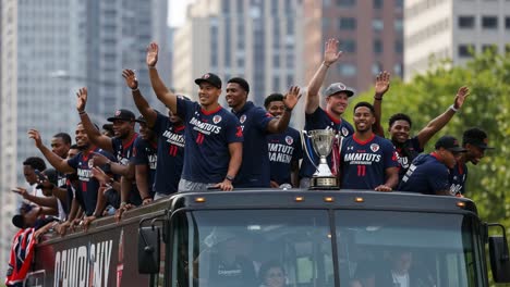 celebrating victory: a team parade in the city, where athletes unite on a bus, enthusiastically waving and showing their championship trophy to the excited crowd below