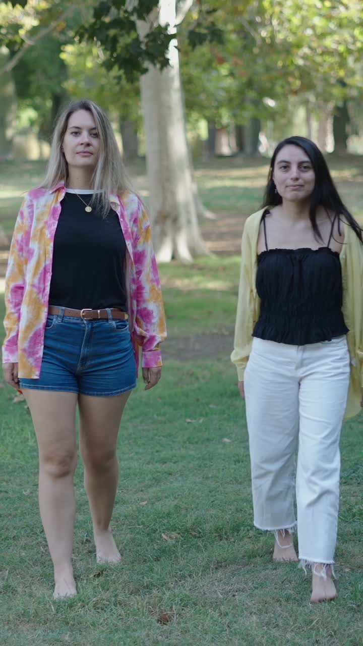 Two women walking barefoot in a park