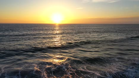 drone shot flying over the sea at sunset on the coast of california