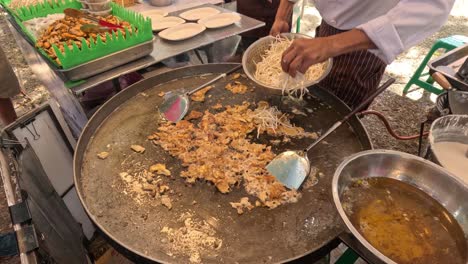 cooking and serving noodles at an outdoor stall