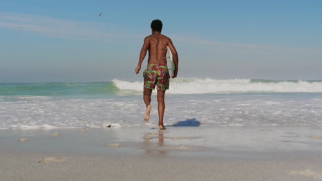 male surfer running towards sea at beach 4k