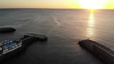 Vista-Aérea-De-La-Puesta-De-Sol-Amarilla-Dorada-Sobre-El-Agua-Del-Océano-Hacia-El-Horizonte-Vista-Desde-El-Club-De-Playa-Bikini-En-Cabo-Verde