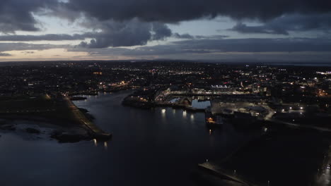 aerial dolly capturing galway city at twilight, city lights glowing under dramatic sky