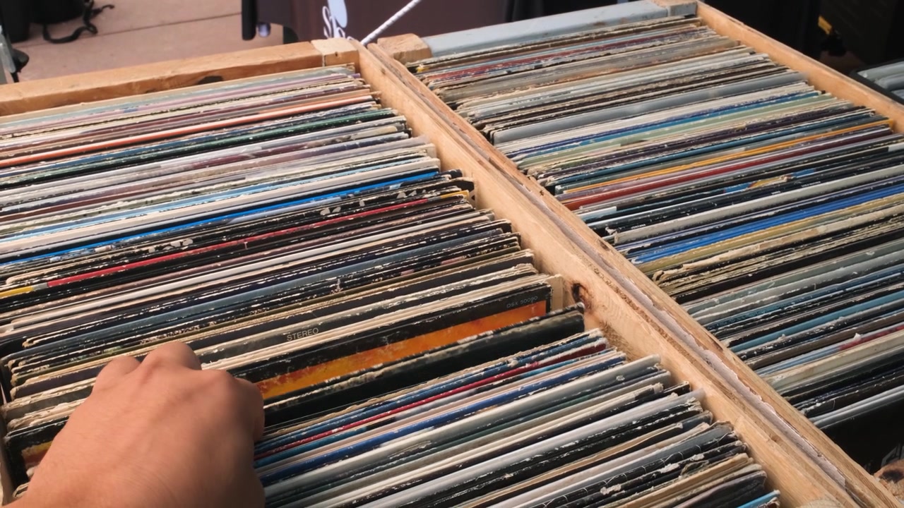 A shopper flips through crates of vintage vinyl records at Market in the Park et in City Park Denver Colorado