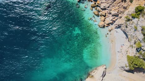 Drohne-Von-Oben-Nach-Unten,-Statischer-Blick-Auf-Türkisfarbenes-Wasser-Und-Felsige-Küste-Am-Weißen-Sandstrand