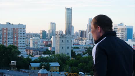 man looking at the city skyline at sunset.