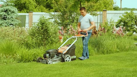 lawn mower cutting the grass. gardening activity. cutting grass with petrol driven lawn mower in sunny garden. gardener working with  mower machine in the garden. lawn mower cutting green grass