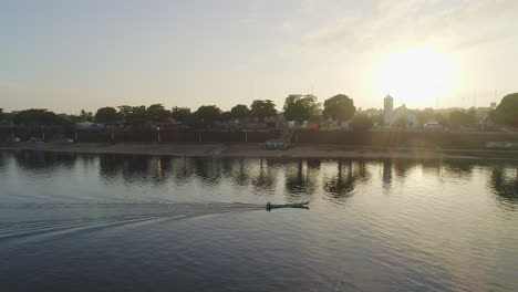 aerial shot drone following small boat on amazonian river near city