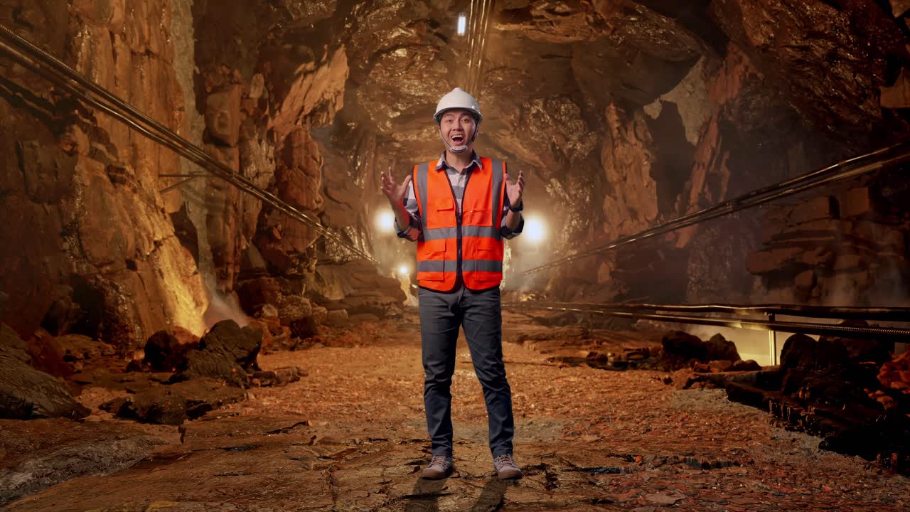 Full Body Of Asian Male Engineer With Safety Helmet Smiling To Camera And Saying Wow While Standing In Underground Mine Tunnel