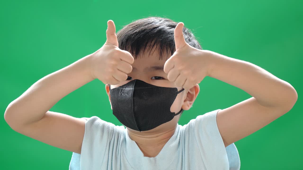 asian chinese toddler wearing black face mask with green background