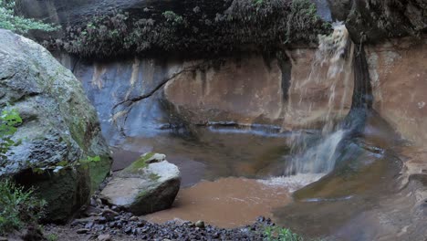 el agua de la inundación marrón forma una pequeña cascada en el cañón de liphofung, lesotho