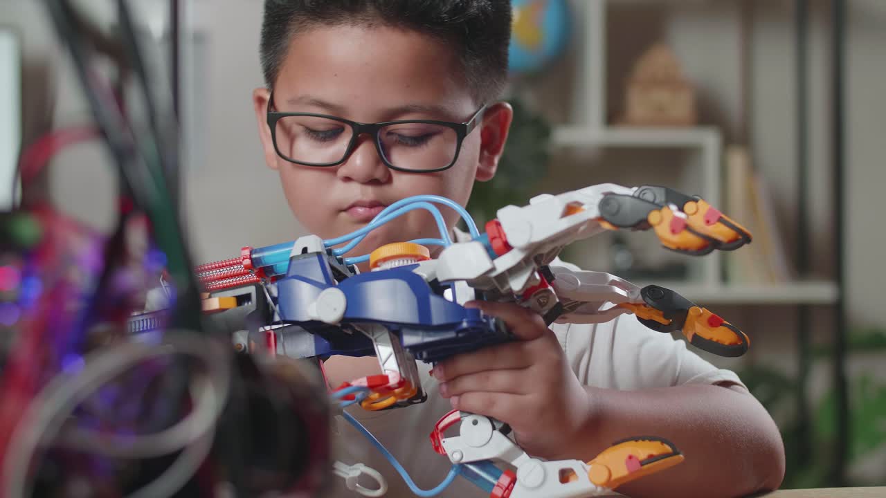 de cerca de un chico asiático lindo mirando el control de una mano cyborg en casa