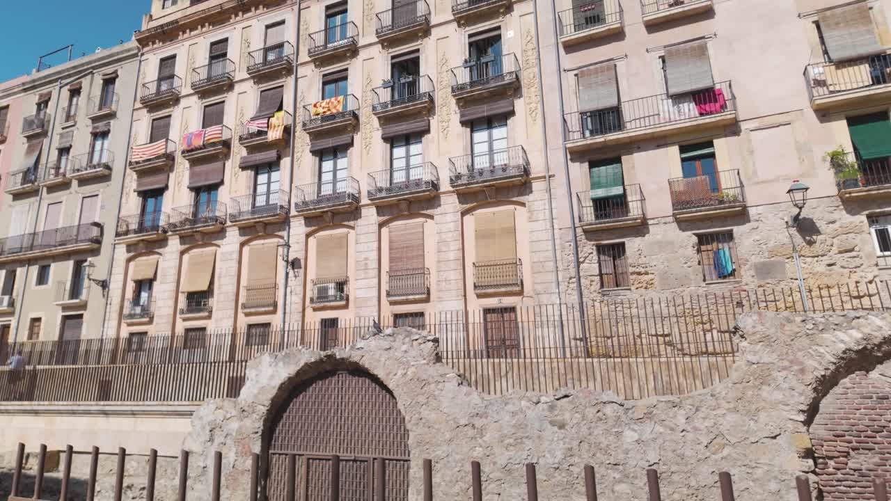 Historic buildings with Roman ruins in Tarragona, Spain, under a bright blue sky
