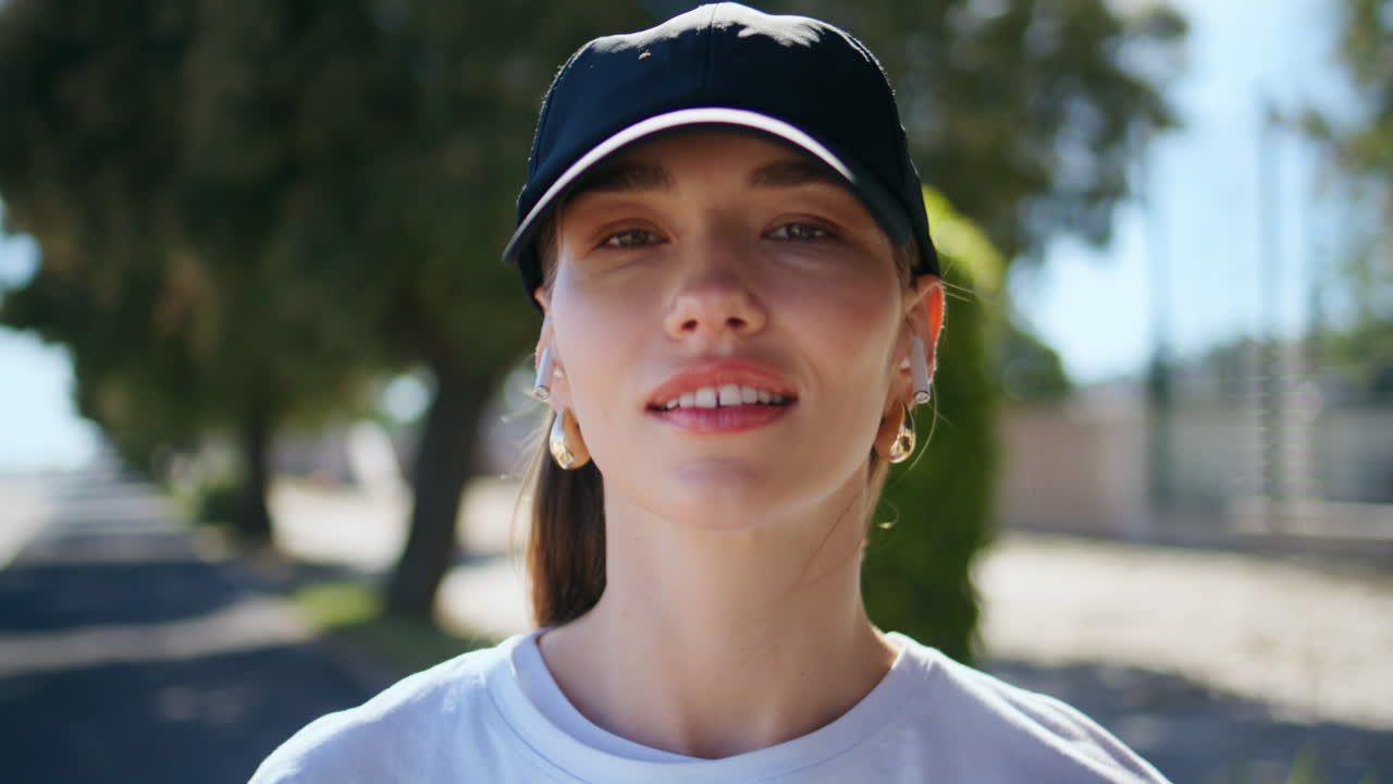 Happy girl adjusting hair smiling to camera at sunny street closeup portrait