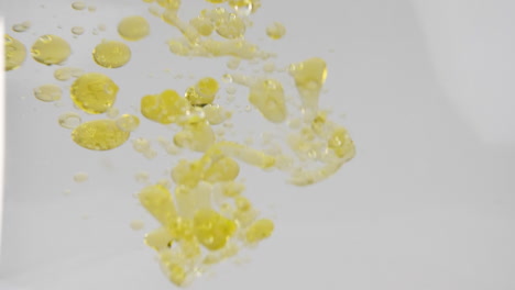 Yellow-color-vegetable-oil-pouring-into-water-forming-bubbles