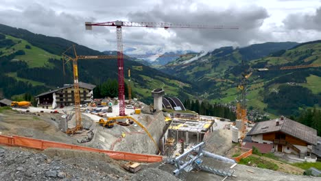 pan aerial shot of gigantic construction site in mountains during cloudy day - build of new modern ski lift resort in austria