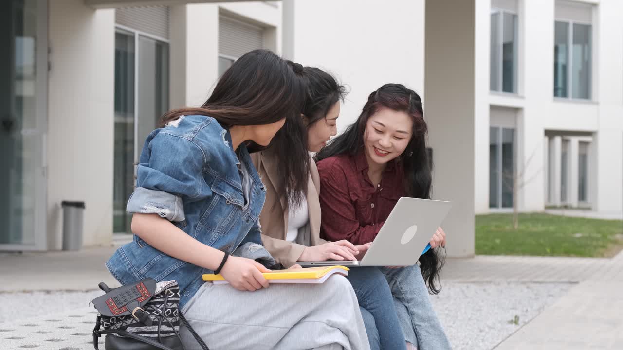 three asian girl students using the laptop at break time sitting on campus